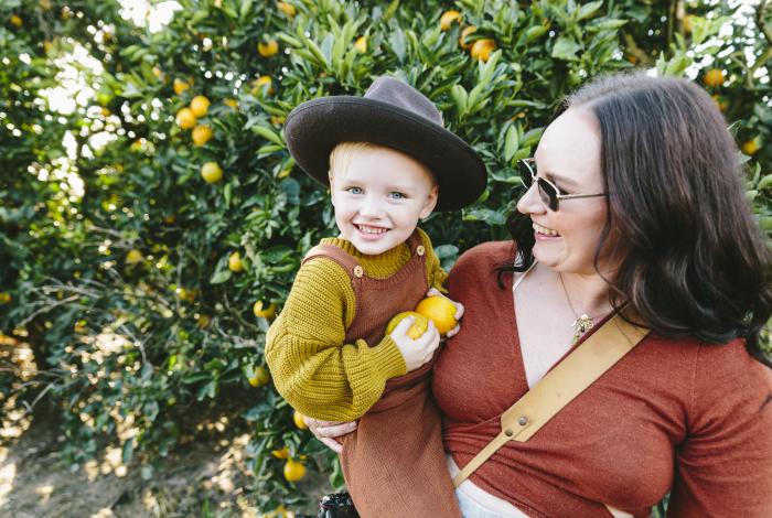 Woman holding a toddler in an orchard